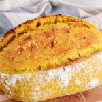 View on a homemade turmeric sourdough bread in a batard on a cutting board.