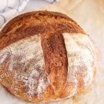 View on a perfect boule of rustic sourdough bread on parchment paper.