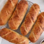 Overhead view on a few sourdough sandwich rolls cooling down on a cooling rack.