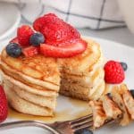 View on a stack of vegan sourdough pancakes made with bananas and garnished with berries.