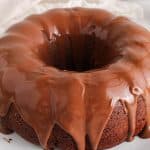 Vegan chocolate bundt cake with a chocolate ganache on a white plate.