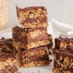 A few squares of no bake oatmeal bars made with peanut butter and including a chocolate-peanut butter middle layer.