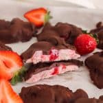Sliced strawberry yogurt clusters covered with chocolate over parchment paper.