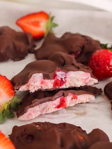 Sliced strawberry yogurt clusters covered with chocolate over parchment paper.