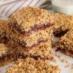 Vegan date square piled over each other over parchment paper.