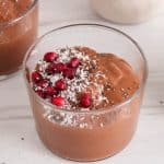 Blended chocolate chia pudding garnished with shredded coconut and pomegranate seeds.