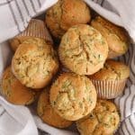 Vegan sourdough zucchini muffins in a bowl with a hand towel.