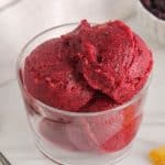 A see-through bowl filled with some blueberry peach sorbet.
