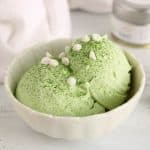 A bowl of vegan coconut matcha ice cream topped with white chocolate chips.