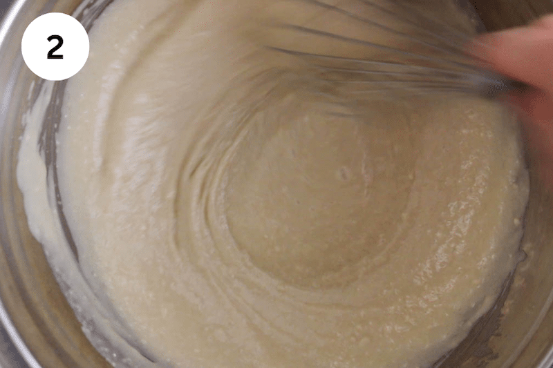 A mixing bowl filled with a cake batter and a whisk mixing.