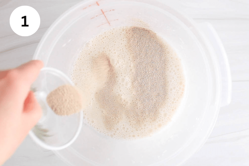 A bowl is sprinkling dry yeast over a large container with sourdough.
