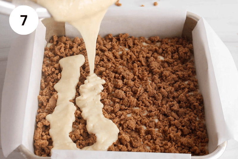 A cake batter pouring over a cinnamon crumble.