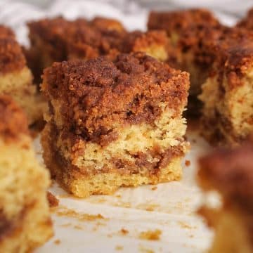 Squares of sourdough discard coffee cake on parchment paper showing the layers of white cake and cinnamon filling.