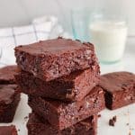 There are a few pieces of vegan sourdough discard brownies piled over each other.