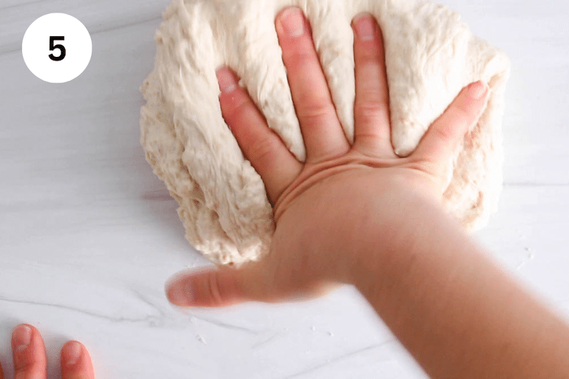 Hand pressing and kneading a ball of dough.