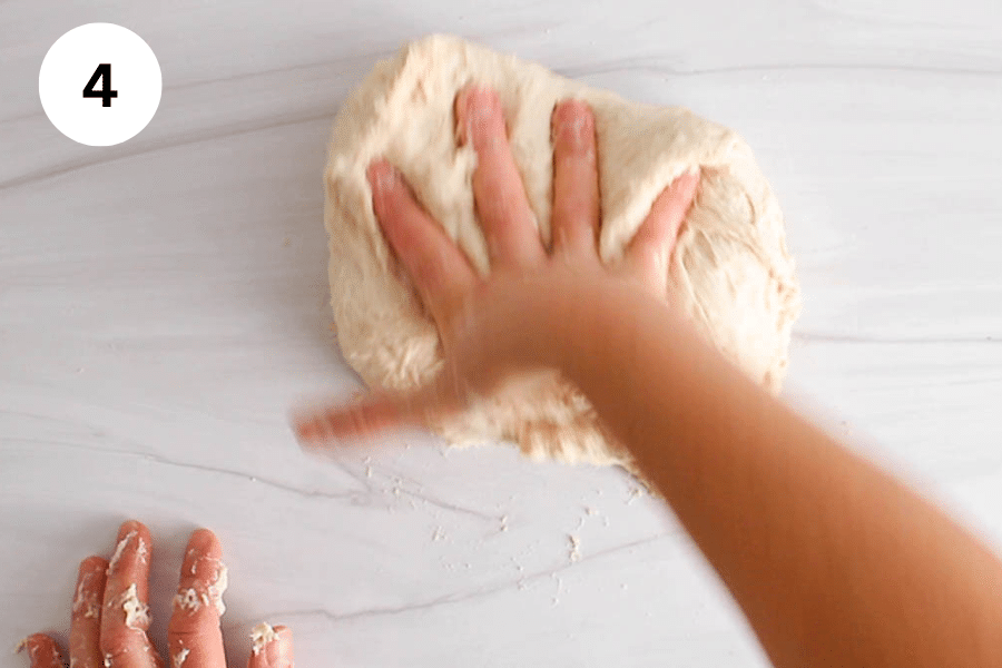 A hand kneading a ball of dough.
