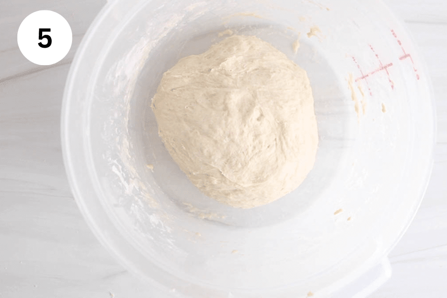 A large container with a ball of dough.