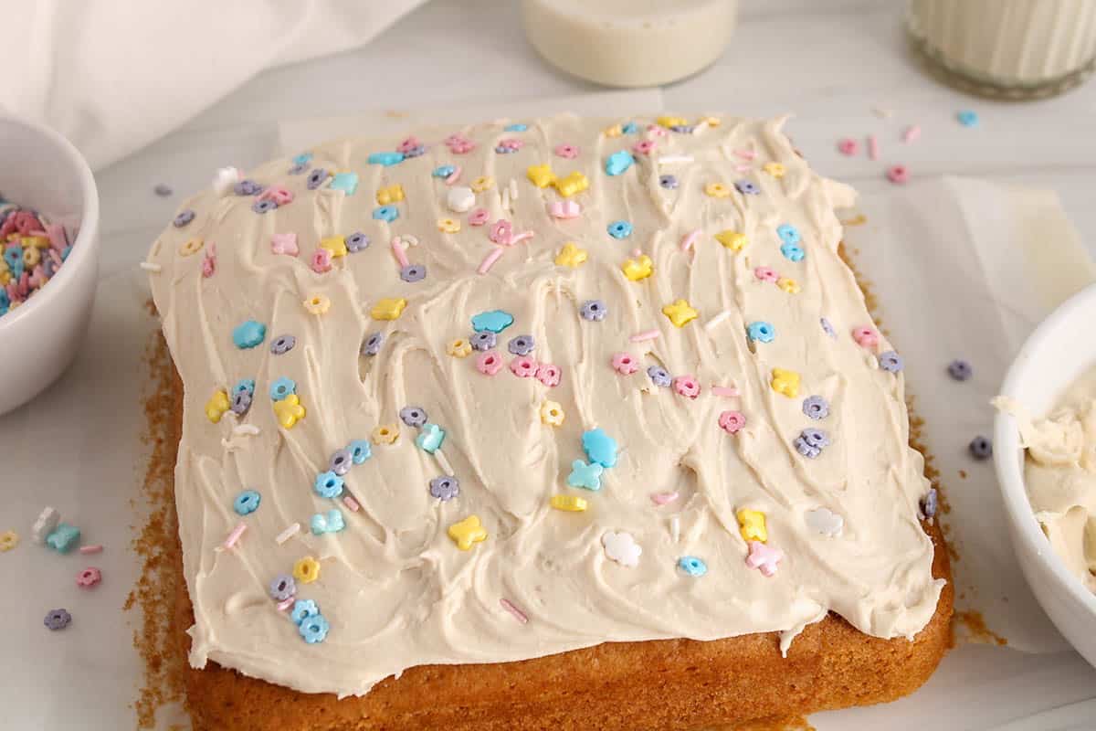 Sourdough vanilla cake covered with white frosting on parchment paper.