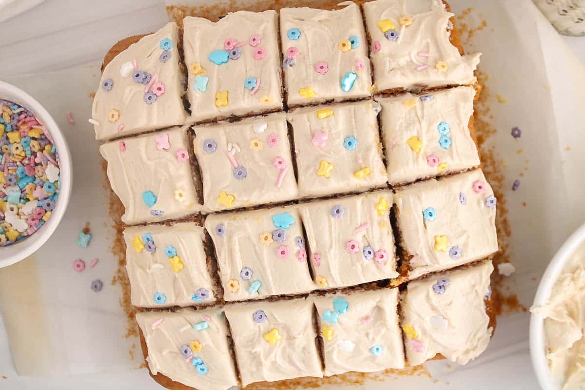 Sourdough vanilla cake covered with white frosting on parchment paper and sliced in squares.