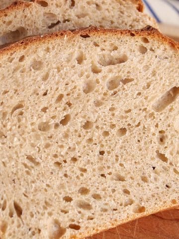 Sliced whole wheat sourdough sandwich bread on a cutting board.