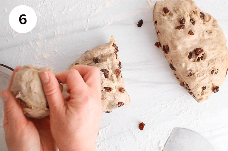 A hand shaping a small piece of dough into a ball.