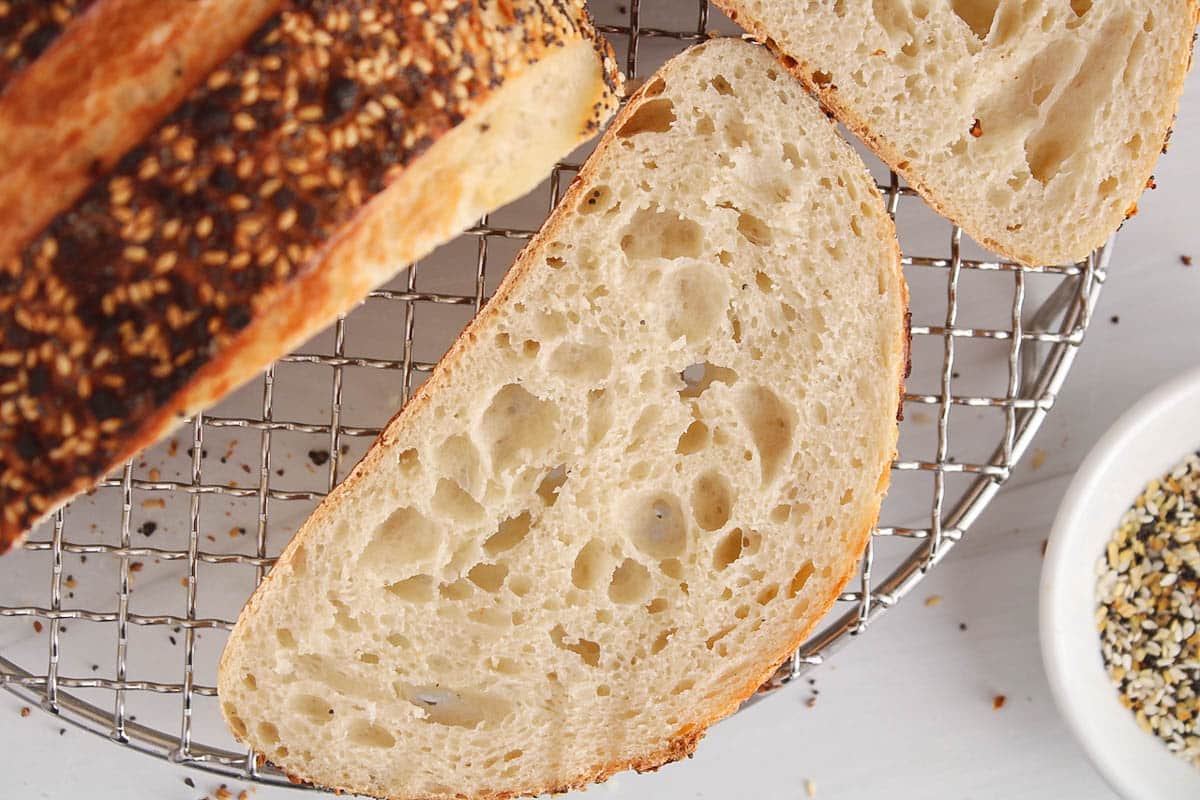 A slice of everything bagel sourdough bread placed on a cooling rack.