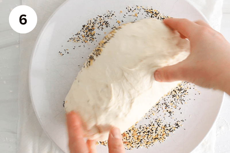 A log of dough rolling over everything bagel seasoning.