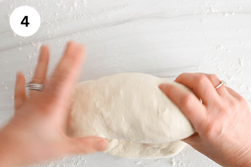 Hands rolling dough into a log.