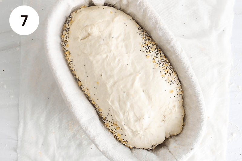 Dough covered with everything bagel seasoning placed in a banneton.