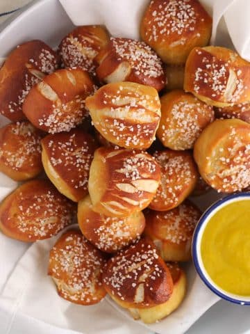 Sourdough discard pretzel bites in a white bowl with a mustard sauce.