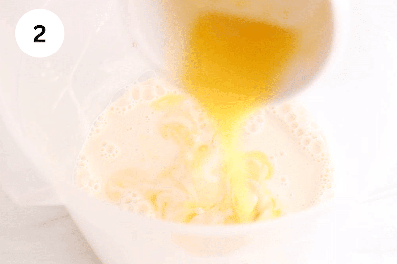 A small bowl pouring melted butter in a container with flour.