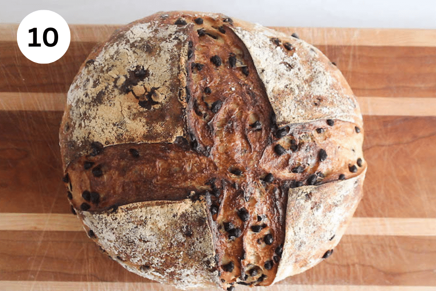 A boule of chocolate chip sourdough bread over a cutting board.