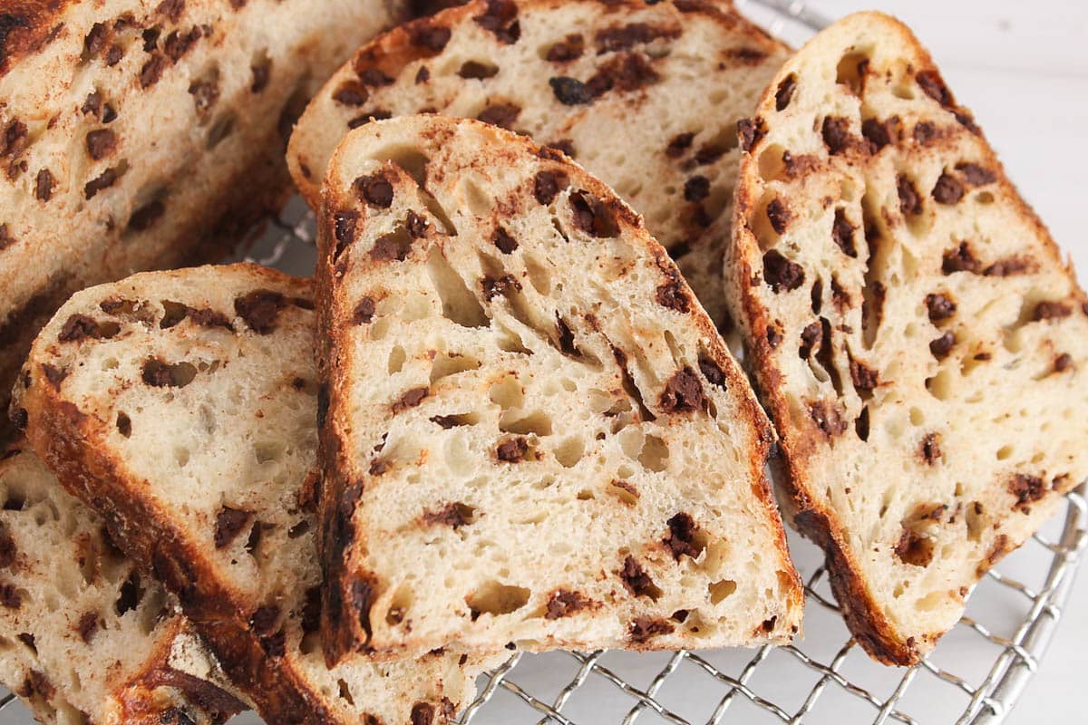 A slice of sourdough bread filled with chocolate chips over a cooling rack.